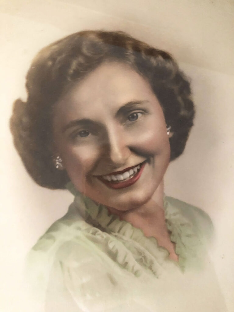 A young photo of Julia with a bright smile, red lipstick, and a green blouse exudes confidence and elegance, capturing her timeless charm and vibrant spirit.