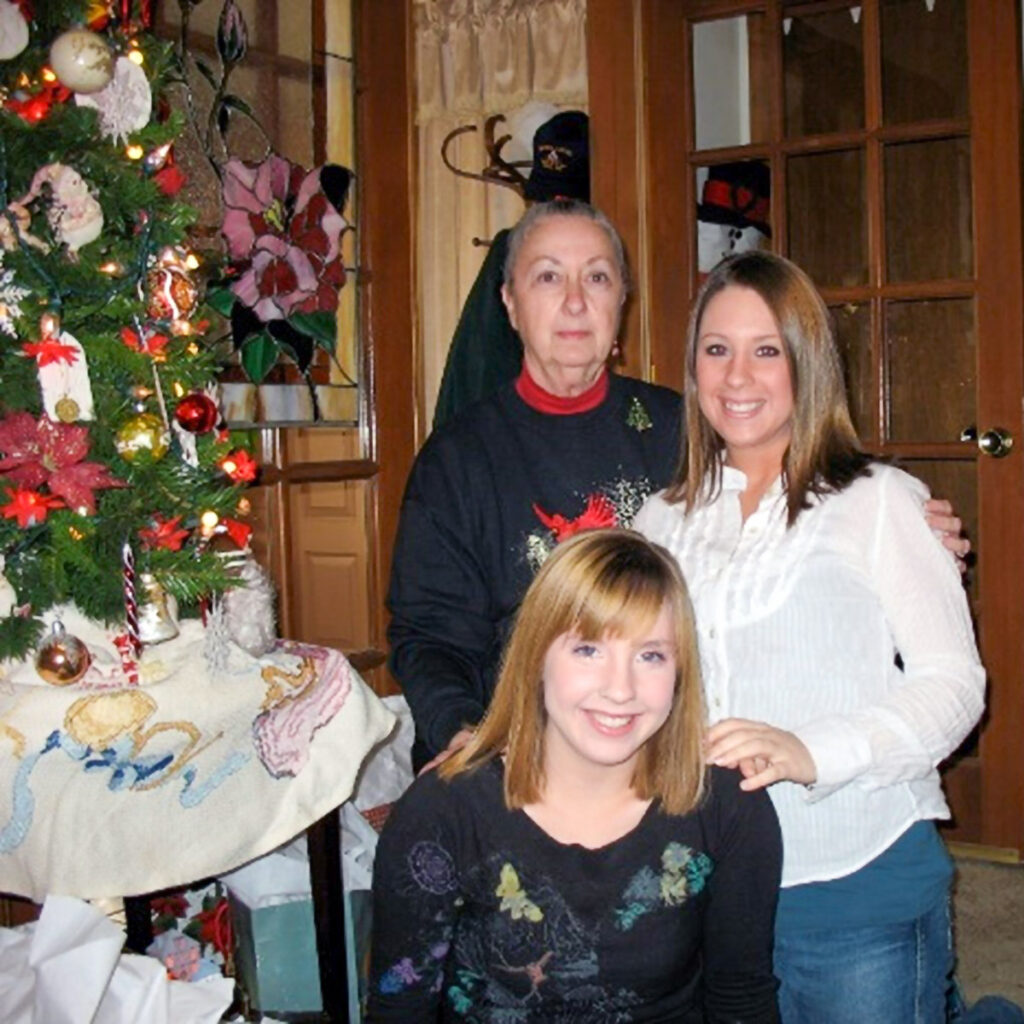 A charming image of Joan in a group photo with holiday decor and has a cheerful expression.