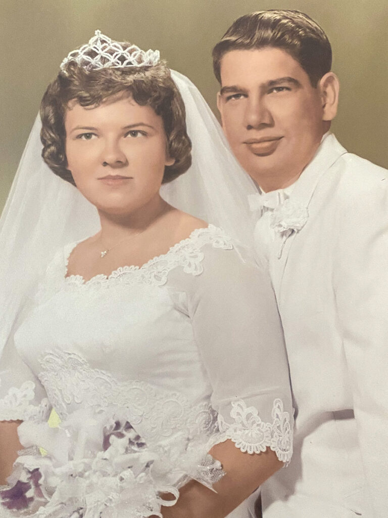 A lovely couple, Carol and Don, in their wedding attire, smiling and posing for a photo on their special day.