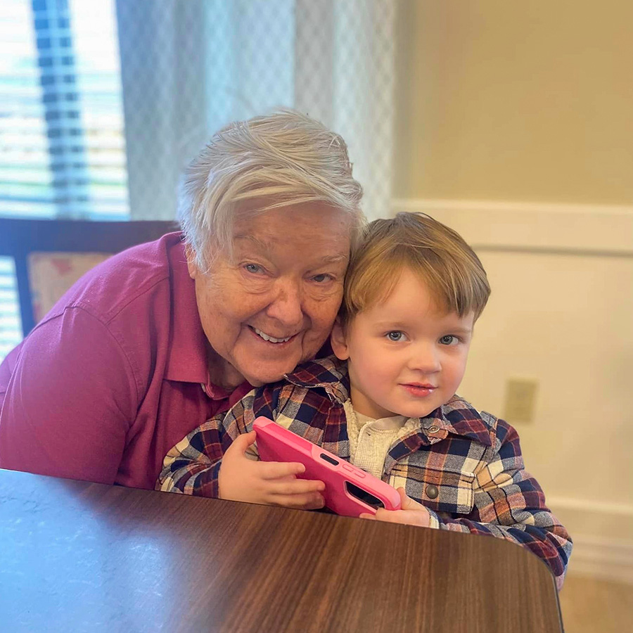 A heartwarming scene of an older woman and a young boy sitting at a table, bonding while volunteering in a senior community.