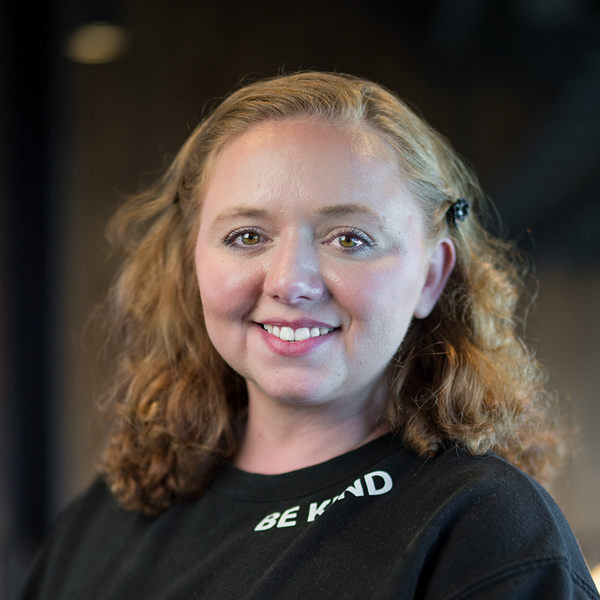 Brittney Rains, Resident Experience Coordinator at Arrow Senior Living, smiles warmly while wearing a black shirt with the words “Be Kind” printed on the collar.