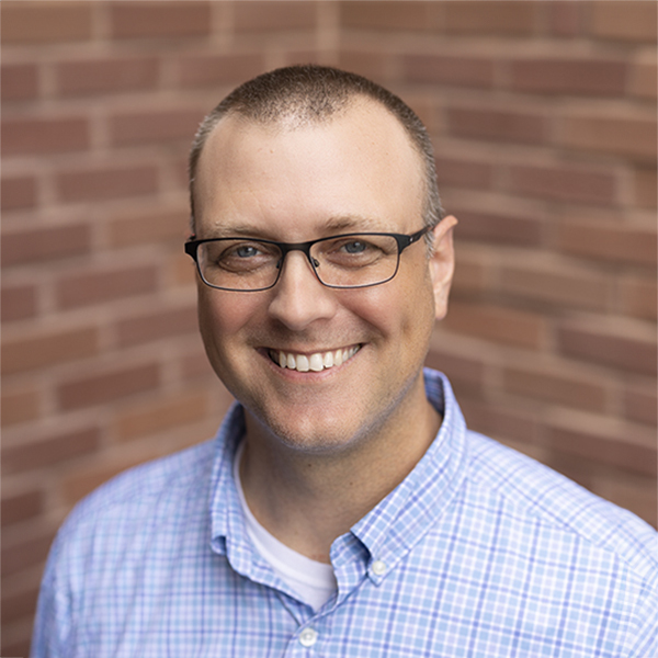 Donald Harris, Integration Manager at Arrow Senior Living, smiling in front of a brick wall background, representing the company’s commitment to operational excellence.