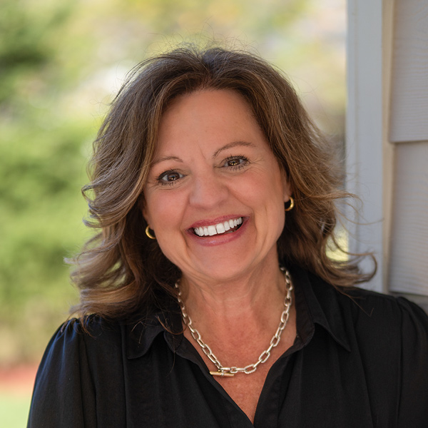 Headshot of Tracy Cecil, Regional Director of Operations at Arrow Senior Living Home Office, wearing a black blouse and gold necklace, smiling in an outdoor portrait setting.