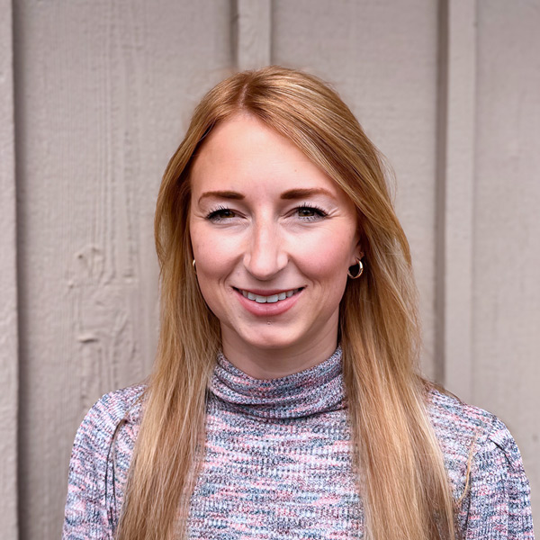 Stefanie Finley, Portfolio Director at Arrow Senior Living Home Office, smiling in a professional headshot, wearing a patterned top, with a neutral wood-paneled background.