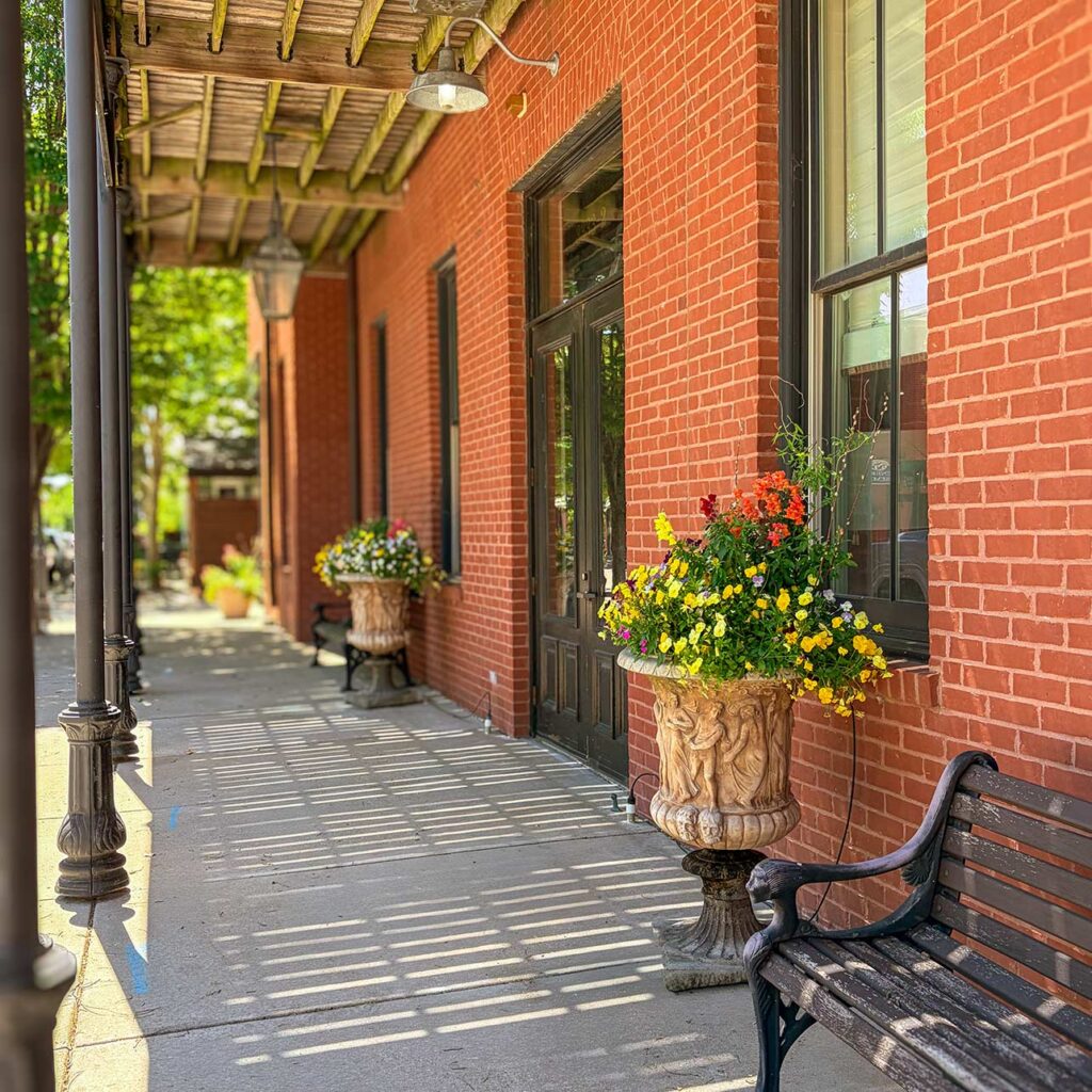 Planters overflowing with flowers adorn the red brick exterior of Arrow Senior Living home office.