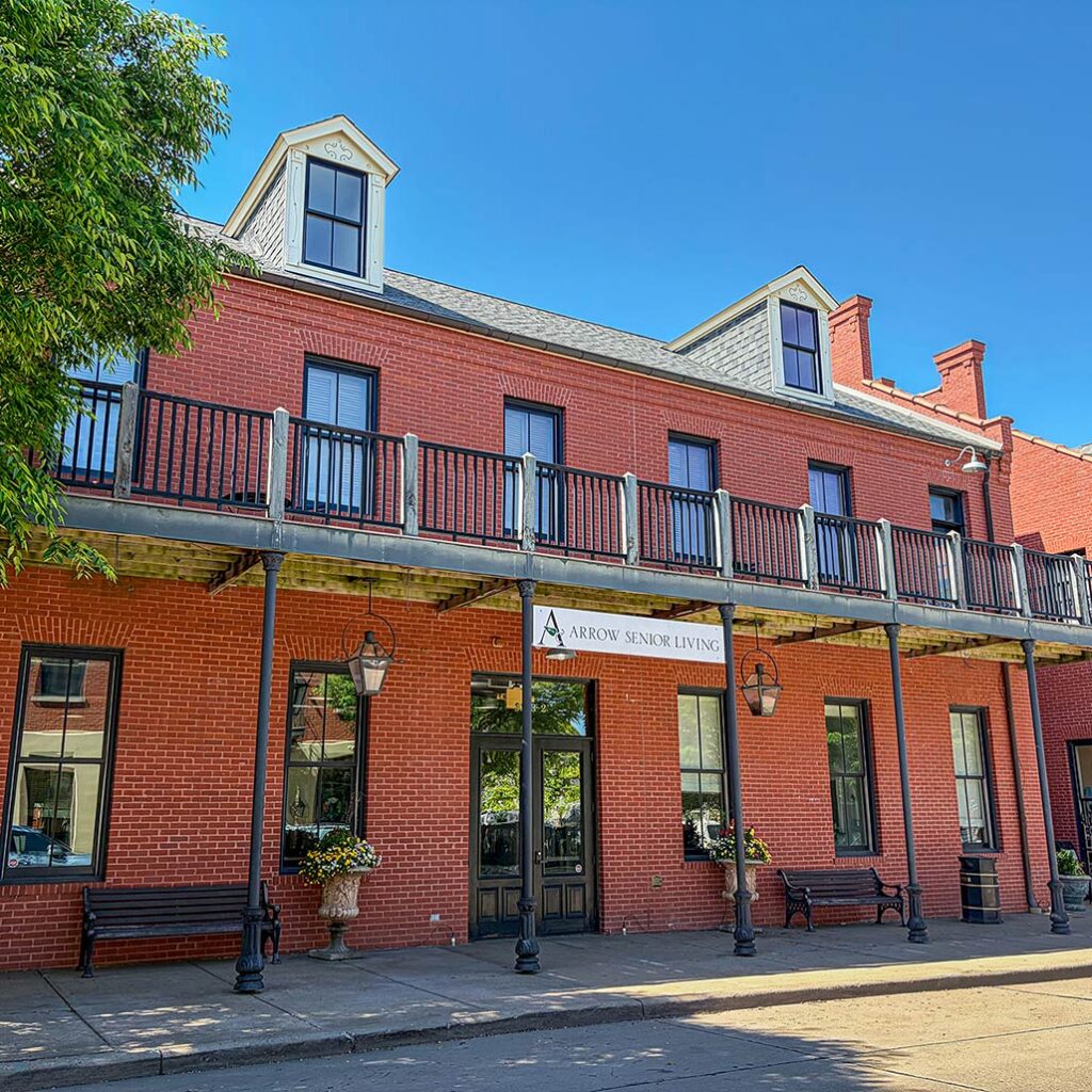 The red brick exterior of Arrow Senior Living home office, featuring carefully chosen planters filled with beautiful flowers.