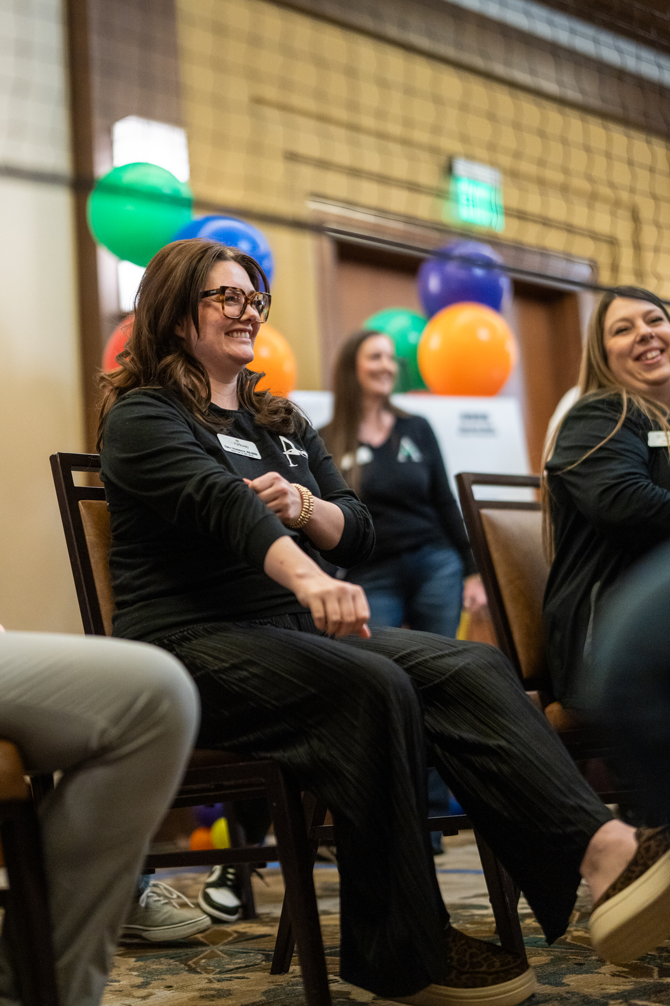 Arrow Senior Living team members smile and participate in a seated activity during a group session.